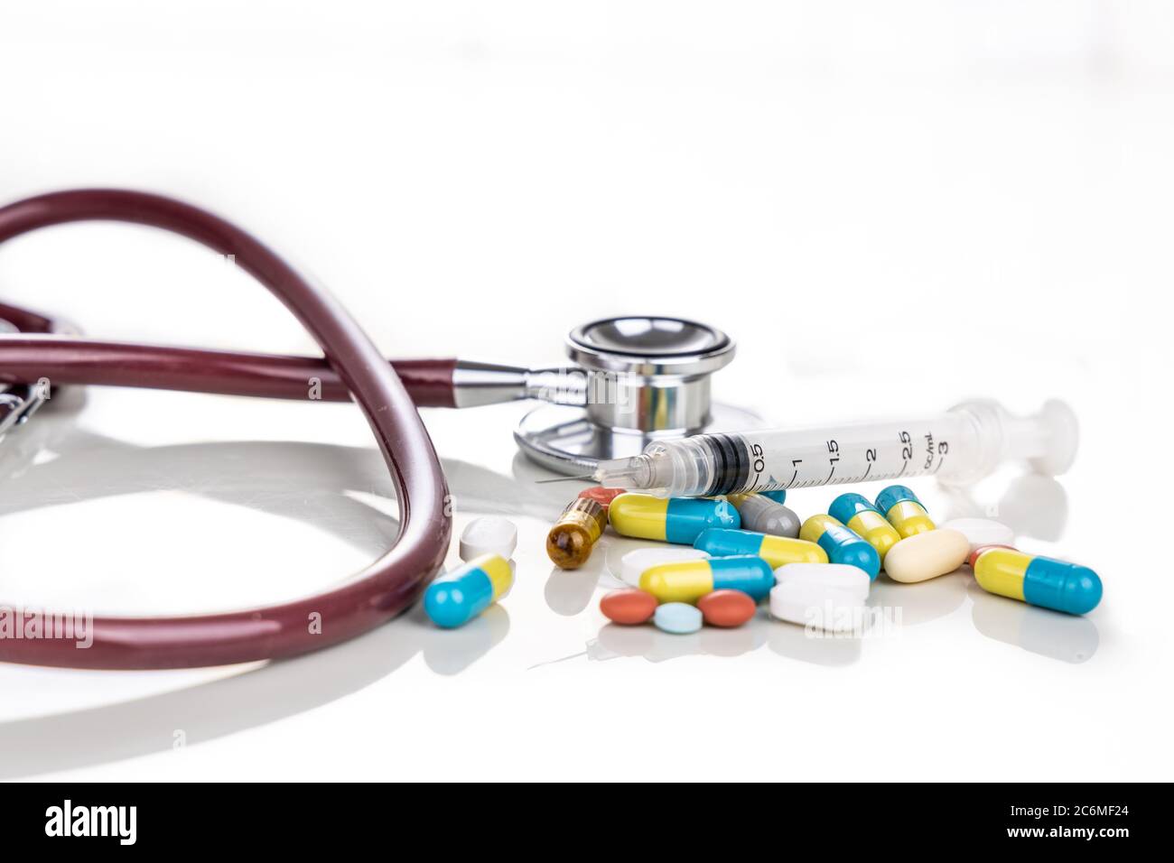 Multiple pills, tablet, caplet, capsule with stethoscope, and syringe