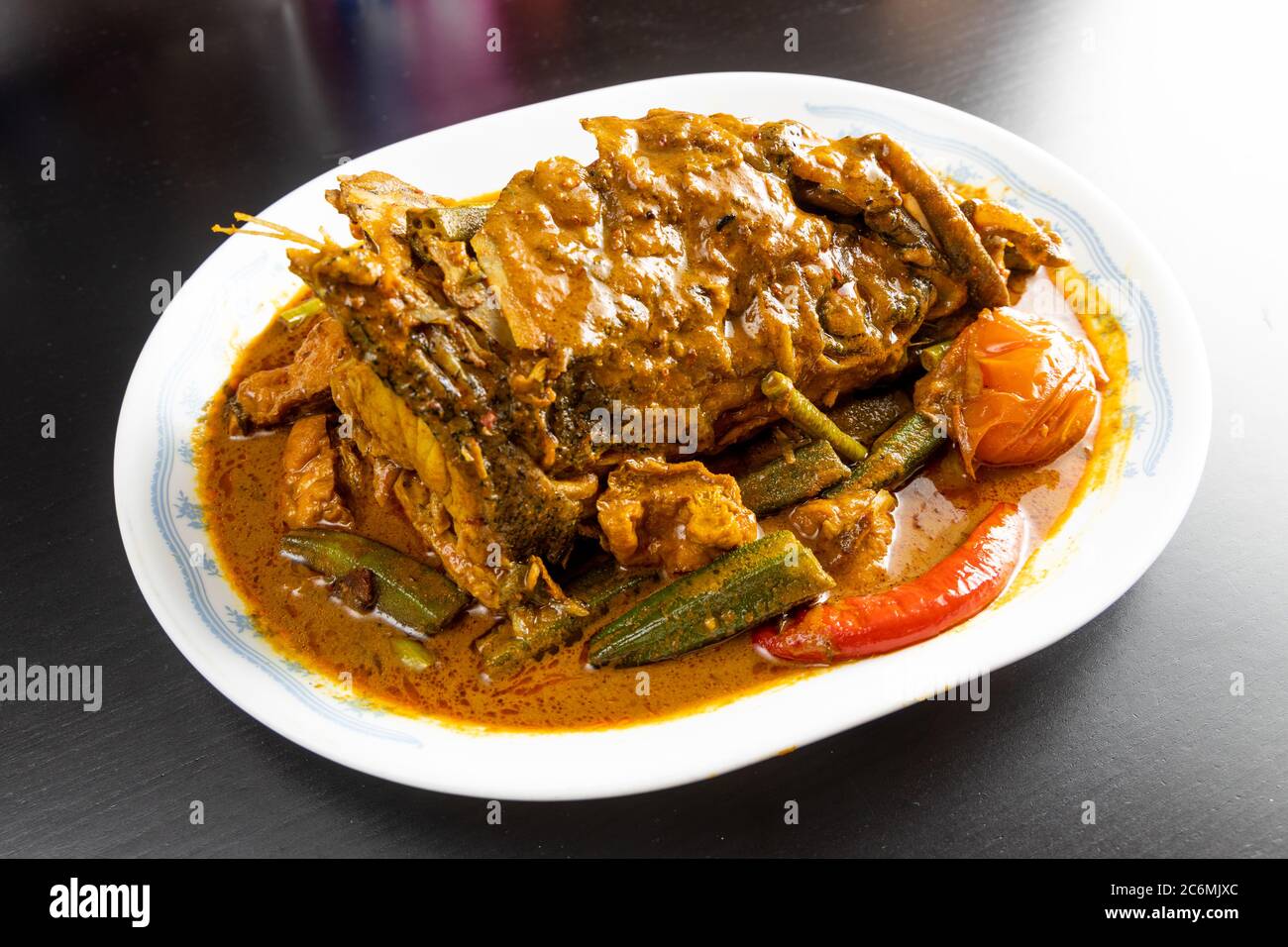 Serving of curry fish head with okra and tomato, popular delicacy in
