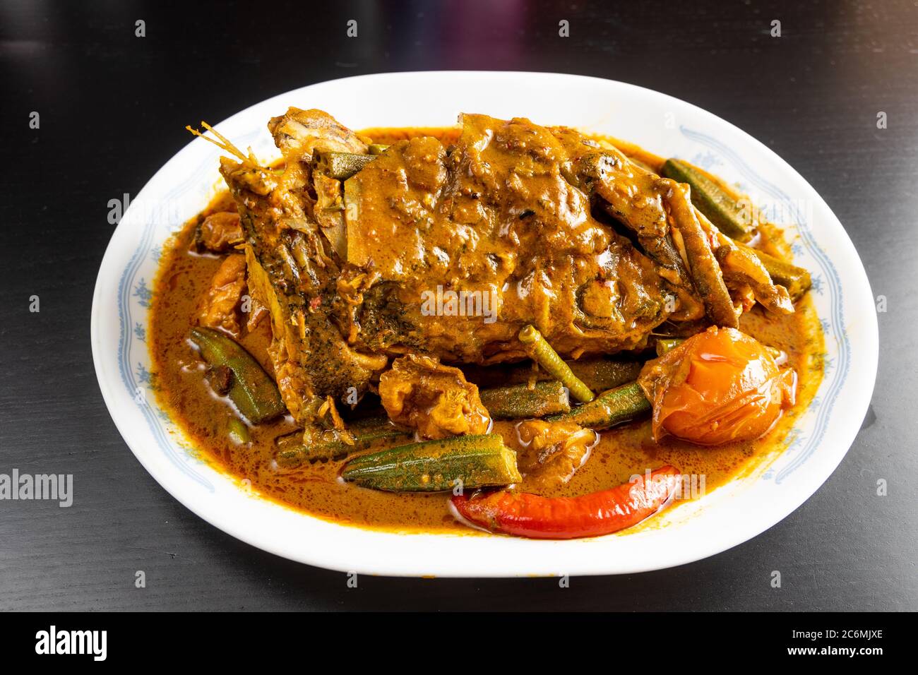 Serving of curry fish head with okra and tomato, popular delicacy in