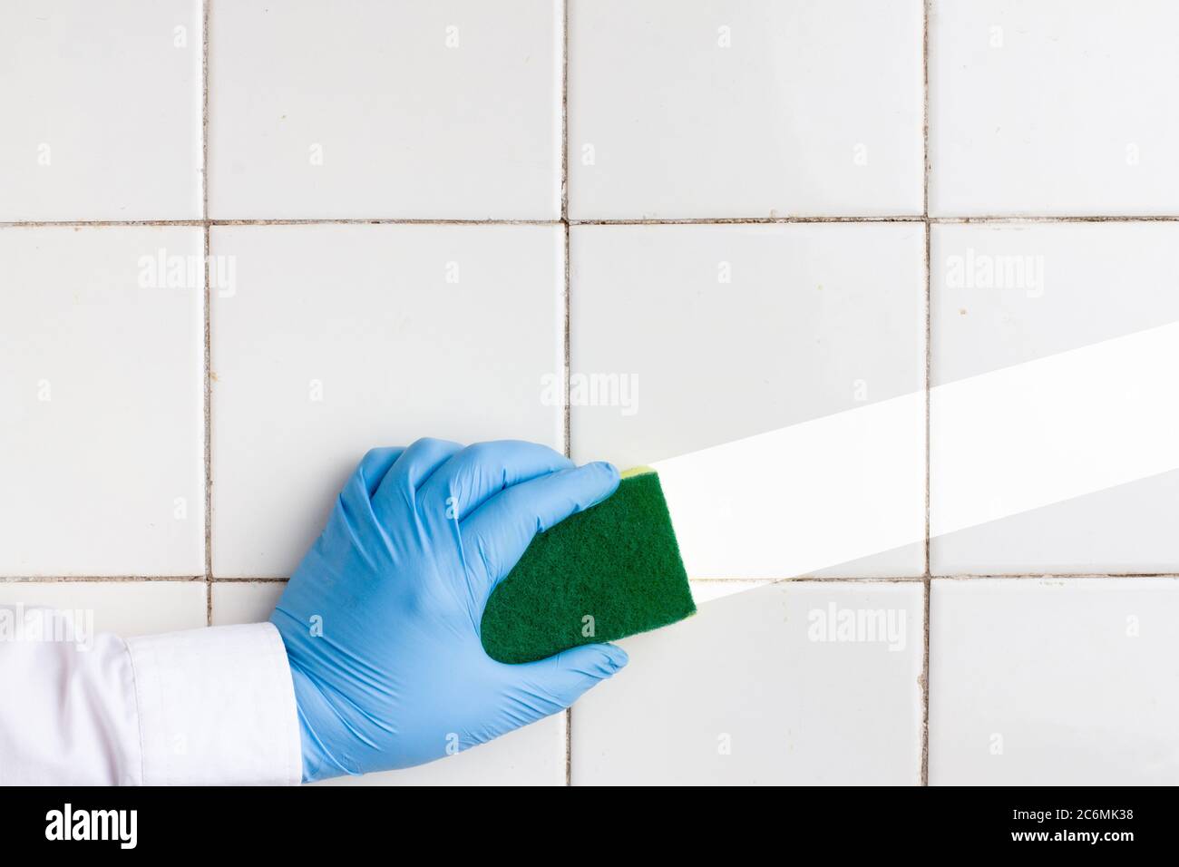 a hand in a blue rubber glove holds a yellow-green microfiber cleaning ...