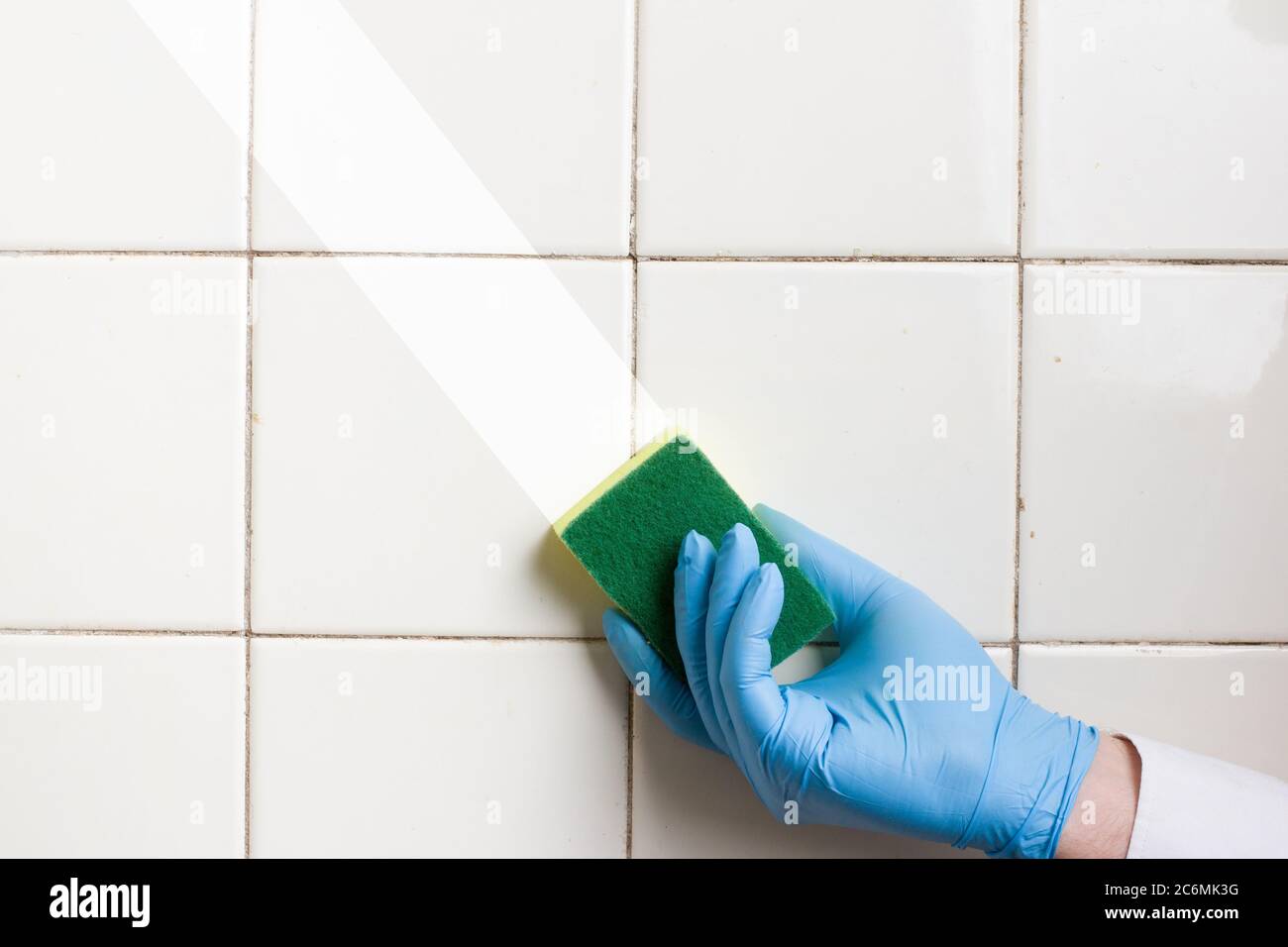 a hand in a blue rubber glove holds a yellow-green microfiber cleaning ...