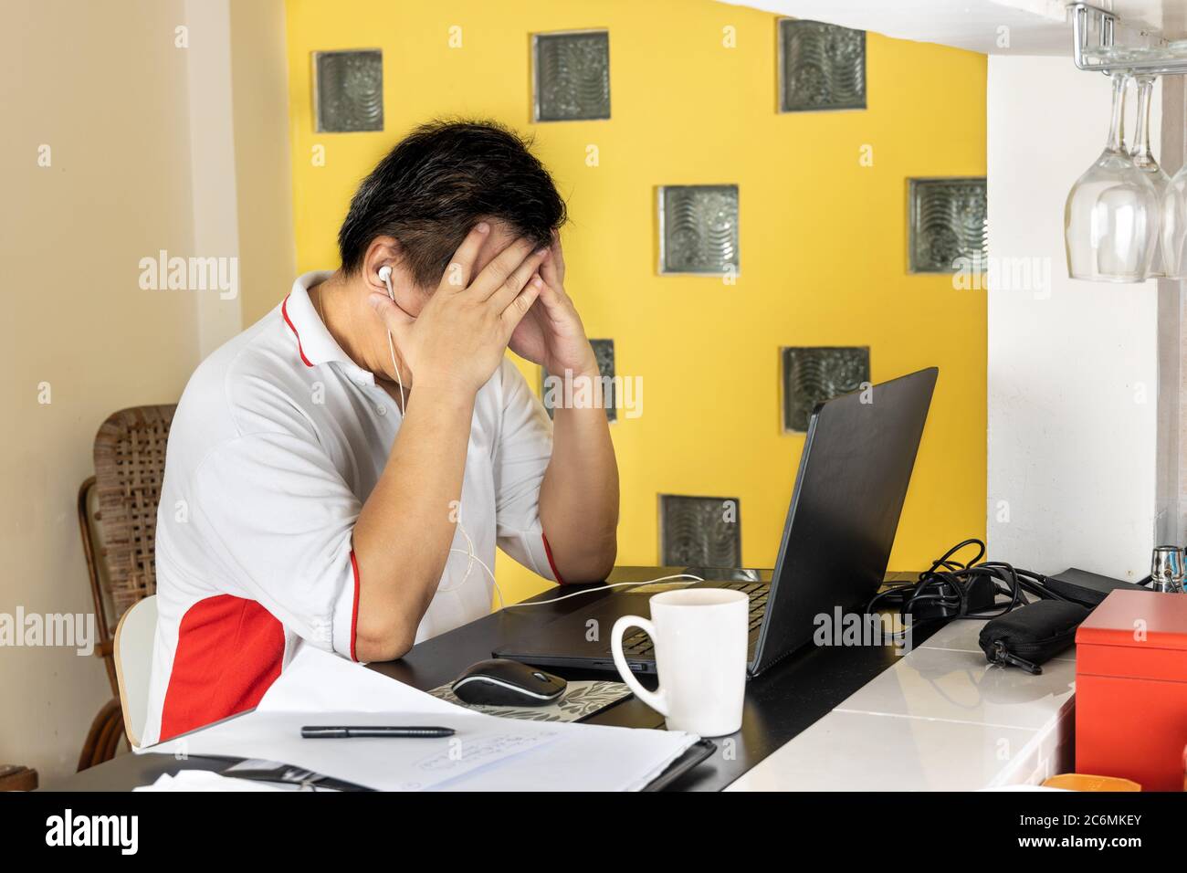 Matured Asian business man with both hands on forehead in stressful expression in work from home video conference call in Malaysia Stock Photo