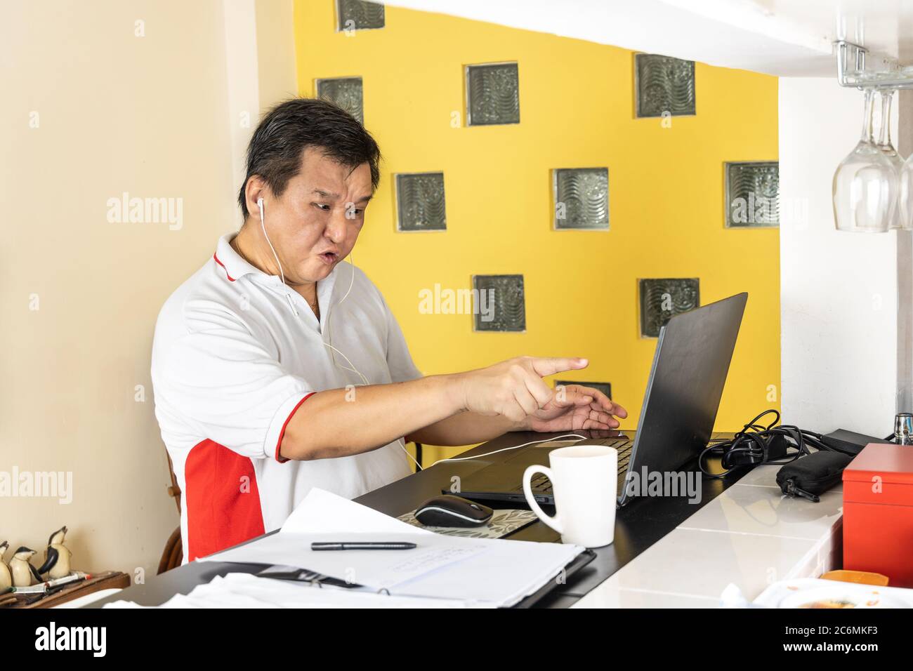 Matured Asian business man pointing to laptop in stressful expression in work from home video conference call in Malaysia Stock Photo