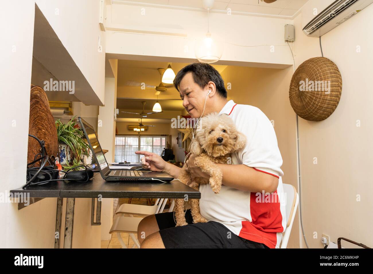 Matured Asian business man work from home accompanied by pet dog during lockdown in Malaysia Stock Photo