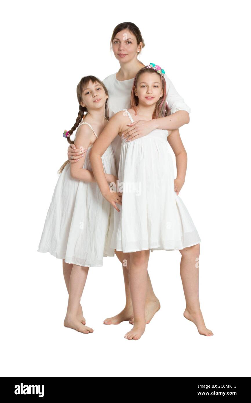 Family mother and two daughters in similar long white dresses. Isolated on white. Stock Photo