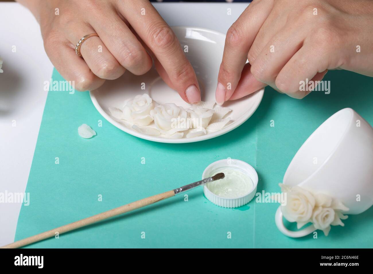 Roses with petals made of white polymer clay. Woman stirs glue with a  brush. Crafts from polymer clay Stock Photo - Alamy