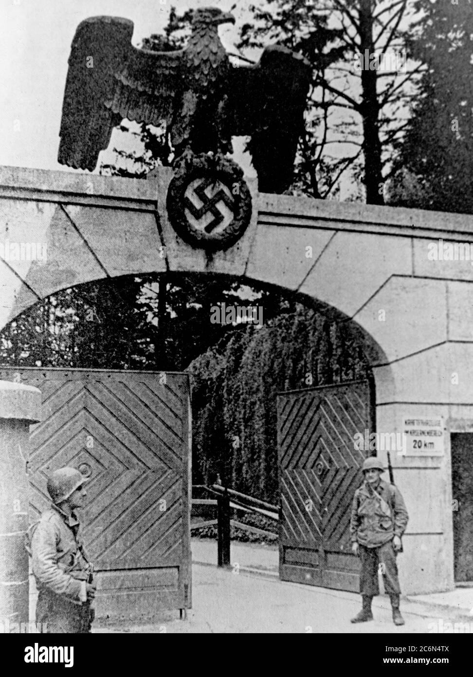 U.S. Army Soldiers stand guard at the SS barracks entrance near the Dachau Concentration Camp following the camp’s liberation, April 29, 1945 in Dachau, Germany. American Soldiers of the U.S. 7th Army, including members of the 42nd Infantry and 45th Infantry and 20th Armored Divisions participated in the camp’s liberation. Stock Photo