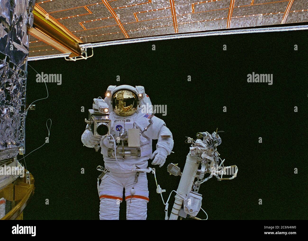 (17 Feb. 1997) --- Astronaut Mark C. Lee, on the end of the Remote Manipulator System (RMS) arm, photographs a bit of patch work on the worn insulation material of the Hubble Space Telescope (HST). The rectangular patch is on HST's Bay 8.  Astronaut Steven L. Smith (out of frame) assisted with the patch work.  This was the final Extravehicular Activity (EVA) of five performed by two teams of space walkers on the STS-82 crew. Stock Photo