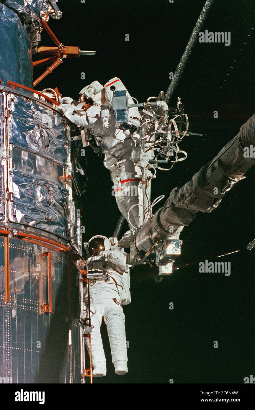 (17 Feb. 1997) --- Astronaut Mark C. Lee (top), on the end of the Remote Manipulator System (RMS) arm, performs a patch task on the worn insulation material of the Hubble Space Telescope (HST).  Astronaut Steven L. Smith assists with the patch work.  This was the final Extravehicular Activity (EVA) of five performed by two teams of space walkers on the STS-82 crew. Stock Photo