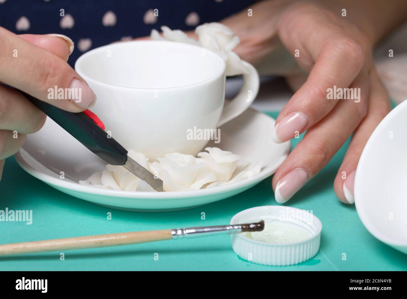 Roses with petals made of white polymer clay. Woman stirs glue with a  brush. Crafts from polymer clay Stock Photo - Alamy