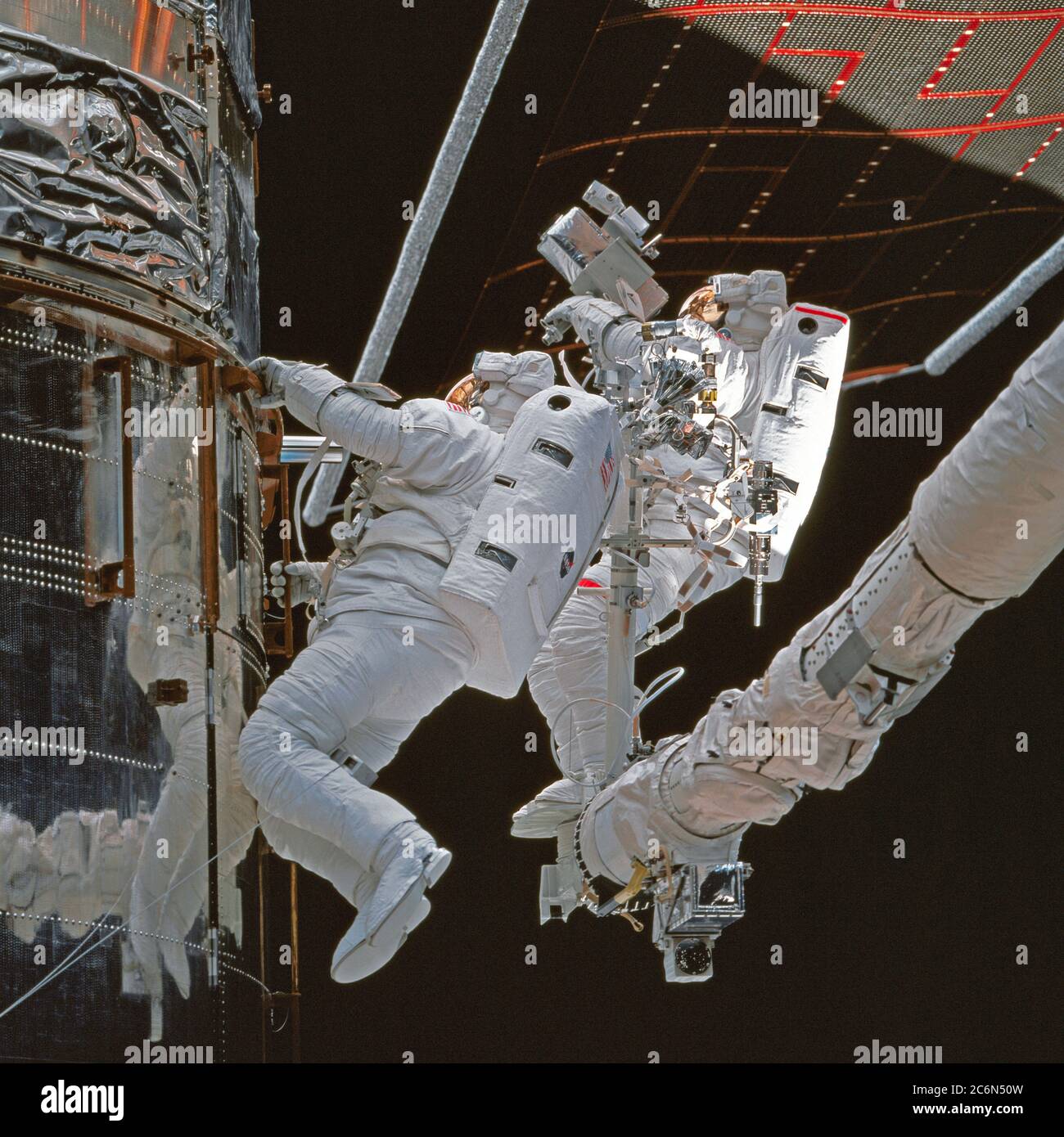 (11-21 Feb. 1997) --- As photographed from inside the Space Shuttle Discovery's crew cabin, astronauts Steven L. Smith (left) and Mark C. Lee (red stripe) inspect insulation around Bay 10 of the Hubble Space Telescope (HST) during one of five days of extravehicular activities (EVA) designed to service the HST.  Lee, payload commander, and Smith, performed three of the five EVA's which eventually were carried out on the mission. Stock Photo