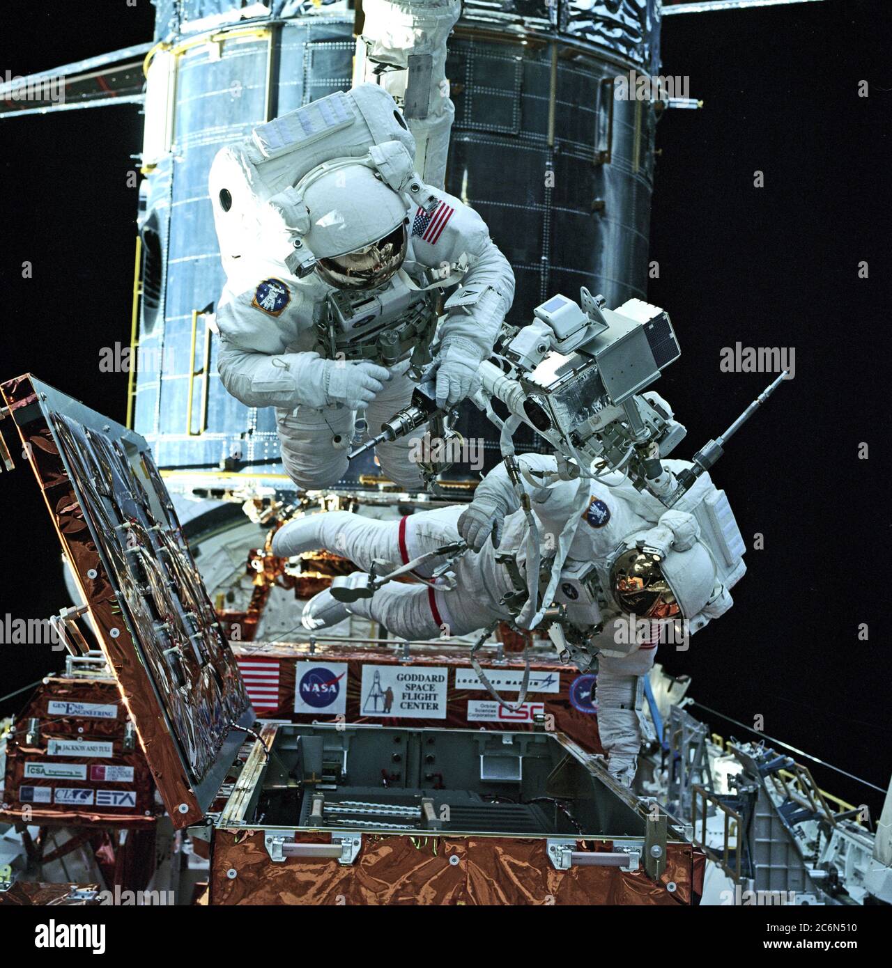 (13 Feb. 1997) --- Gearing up with tools for the first Extravehicular Activity (EVA-1) to service the Hubble Space Telescope (HST, background) are astronauts Steven L. Smith (left) and Mark C. Lee. They were among four STS-82 crewmembers who are to share several alternating two-member space walking work sessions during the flight.  The photograph was made from inside Discovery's cabin with a 70mm camera. Stock Photo