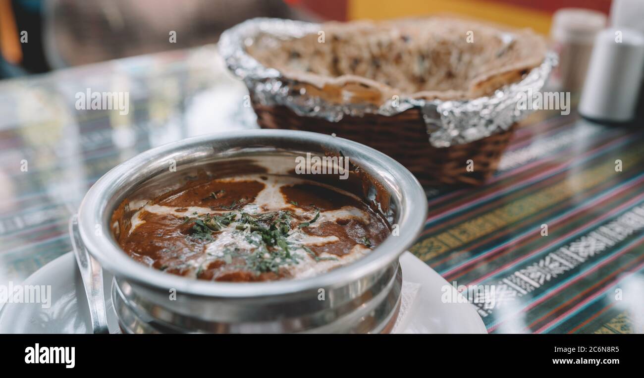 Close up of exotic dish in street cafe. Indian hot dish with spicy seasonings on table in tropical cafe. Stock Photo