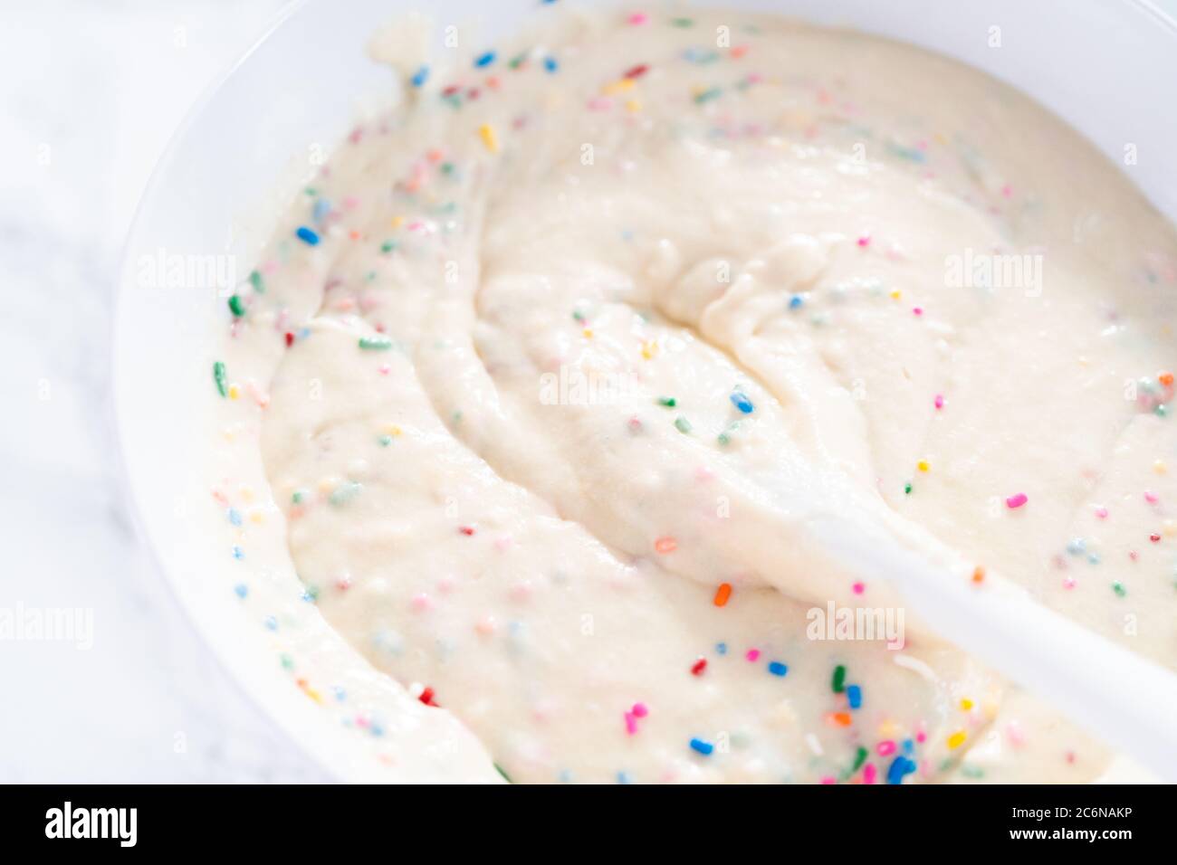 Mixing ingredients to bake birthday funfetti cake with colorful