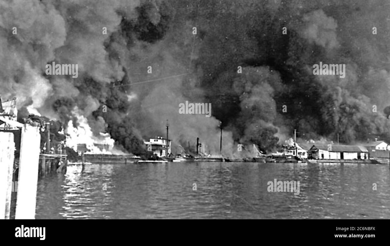 Fires at Cavite Navy Yard resulting from the Japanese air raid on December 10, 1941. Fifty-four bombers of the 11th Air Fleet were detailed from Formosa and attacked at 1300 hours. Twenty-seven attacked ships and small craft in the bay and the attack lasted for two hours. The entire yard was set ablaze; the power plant, dispensary, repair ships, warehouses, barracks, and radio station received direct hits. Greatest damage was done by the fire which spread rapidly and was soon out of control. Adm. Rockwell estimated that five hundred men were killed or seriously wounded. (U.S. Army Photo) Stock Photo