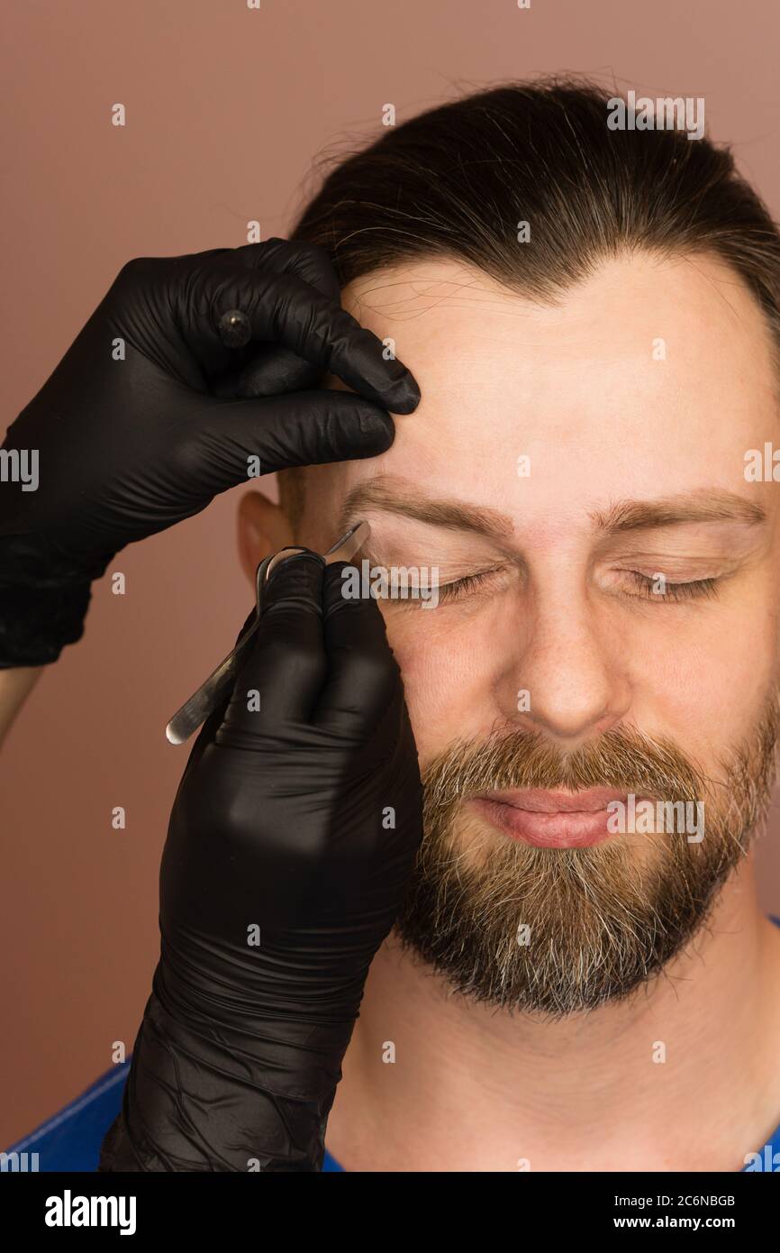 Professional barber doing threading procedure and correcting shape of