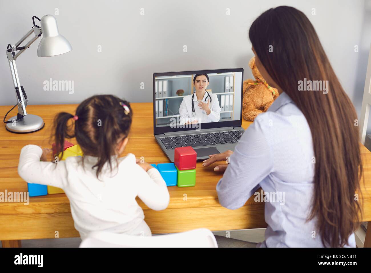 Family doctor online. Mom and daughter listen to the doctor consultation have a video conference in the room. Stock Photo