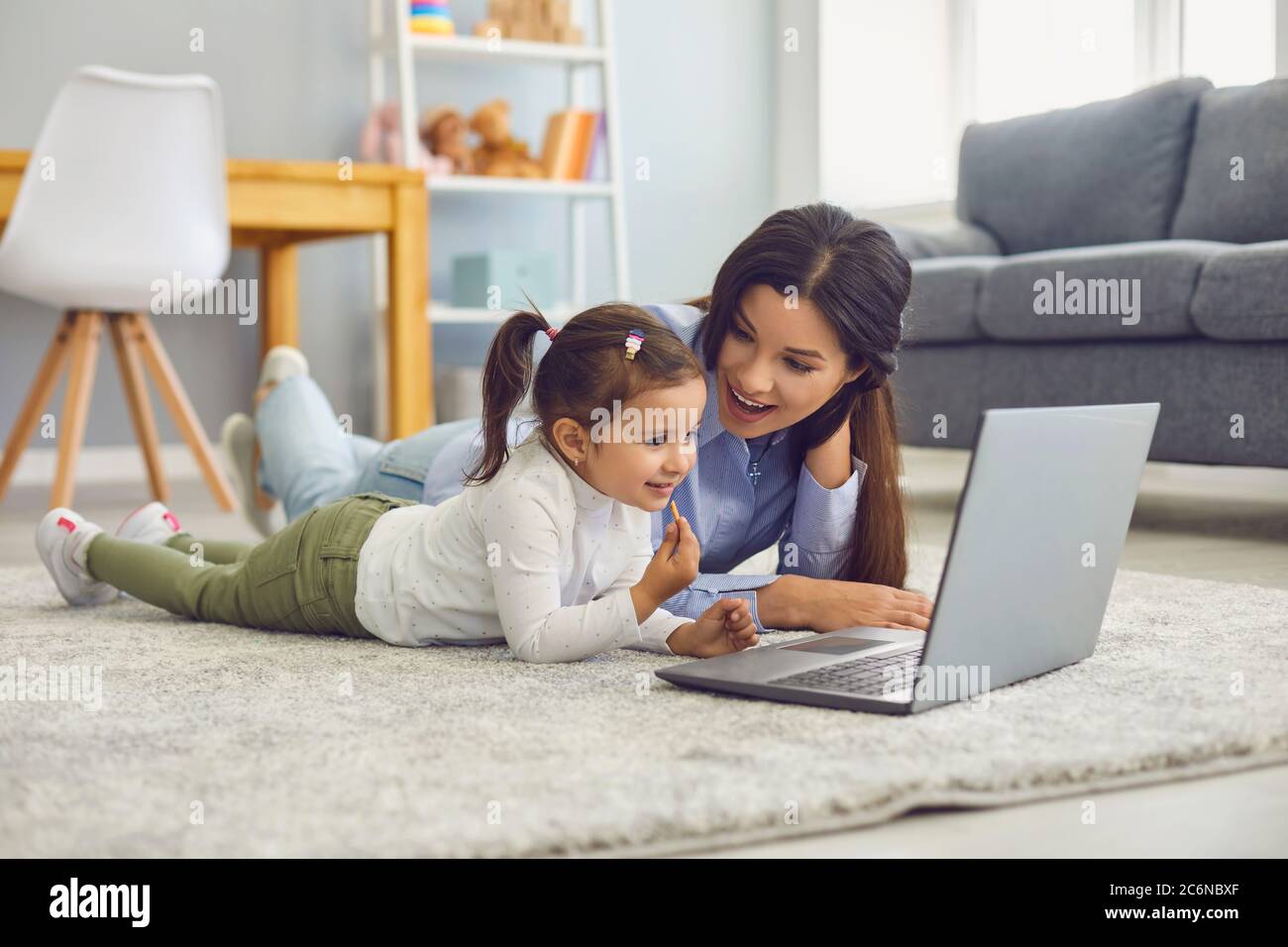 Happy mother and her cute little daughter watching online entertainment video together on laptop at home Stock Photo