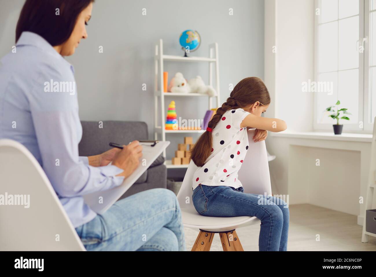 Crying girl on visit to child psychologist at office. Kid suffering from mental problem and psychotherapist at clinic Stock Photo