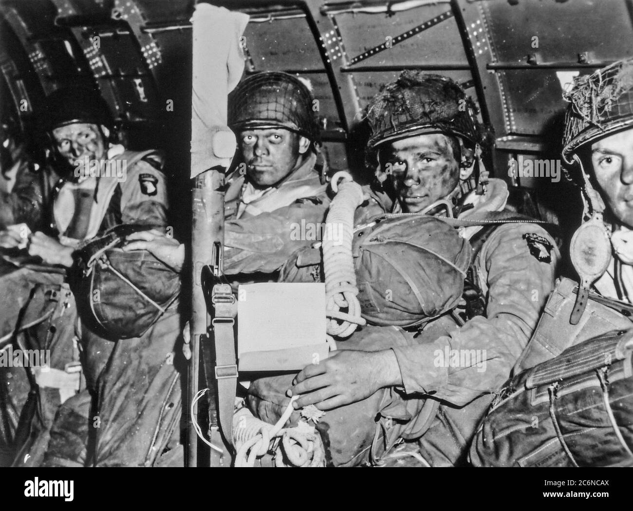 Resolute faces of U.S. Army paratroopers just before they took off for the initial assault of D-Day. The paratrooper in the foreground had just read Gen. Dwight D. Eisenhower's message of good luck and clasped his bazooka in determination. Note Eisenhower's D-Day order in the hands of the paratrooper in the foreground. Stock Photo