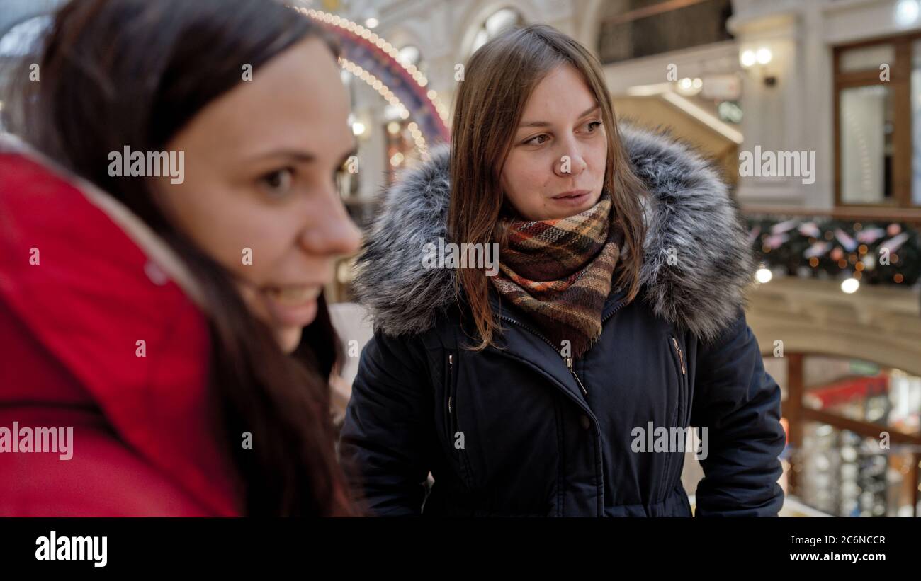 The meeting of the girlfriends. Two women are discussing something in a shopping center. Stock Photo