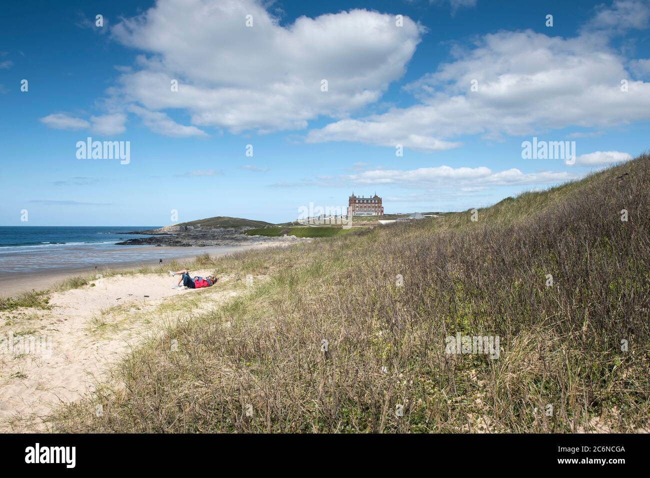 A couple relaxing together in the sand dune system overlooking Fistral Beach in Newquay in Cornwall. Stock Photo