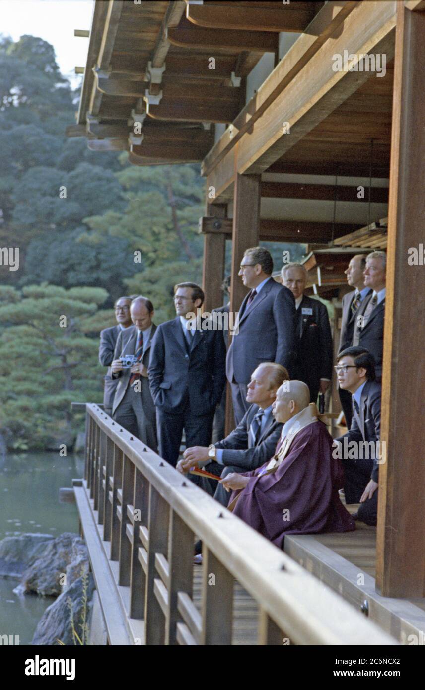 1974, November 21 – Kinkakuji Castle (Gold Pavilion) – Kyoto, Japan – Gerald R. Ford, Zen Buddhist Abbot Jikai Murakami, Interpreter, Secretary of State Henry A. Kissinger,  Donald Rumsfeld; Other Members of US and Japanese Travelling Group – An interpreter sits between President Ford and Zen Buddhist Abbot Jikai Murakami as the two chat in the pavilion above the Cyoko Chi Pond - First Visit to Japan by a Sitting US President - Tour of  Zen Buddhist Shrine - Abbott of Gold Pavilion Stock Photo