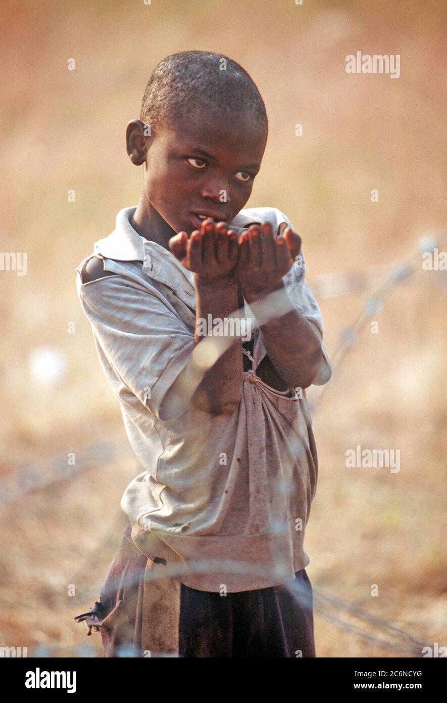 1994 Zaire - A small Rwandan refugee begs for food from United Nations personnel at the Kibumba refugee camp.  He is one of the estimated 1.2 million Rwandan refugees fled to Zaire after a civil war erupted in their country. Stock Photo