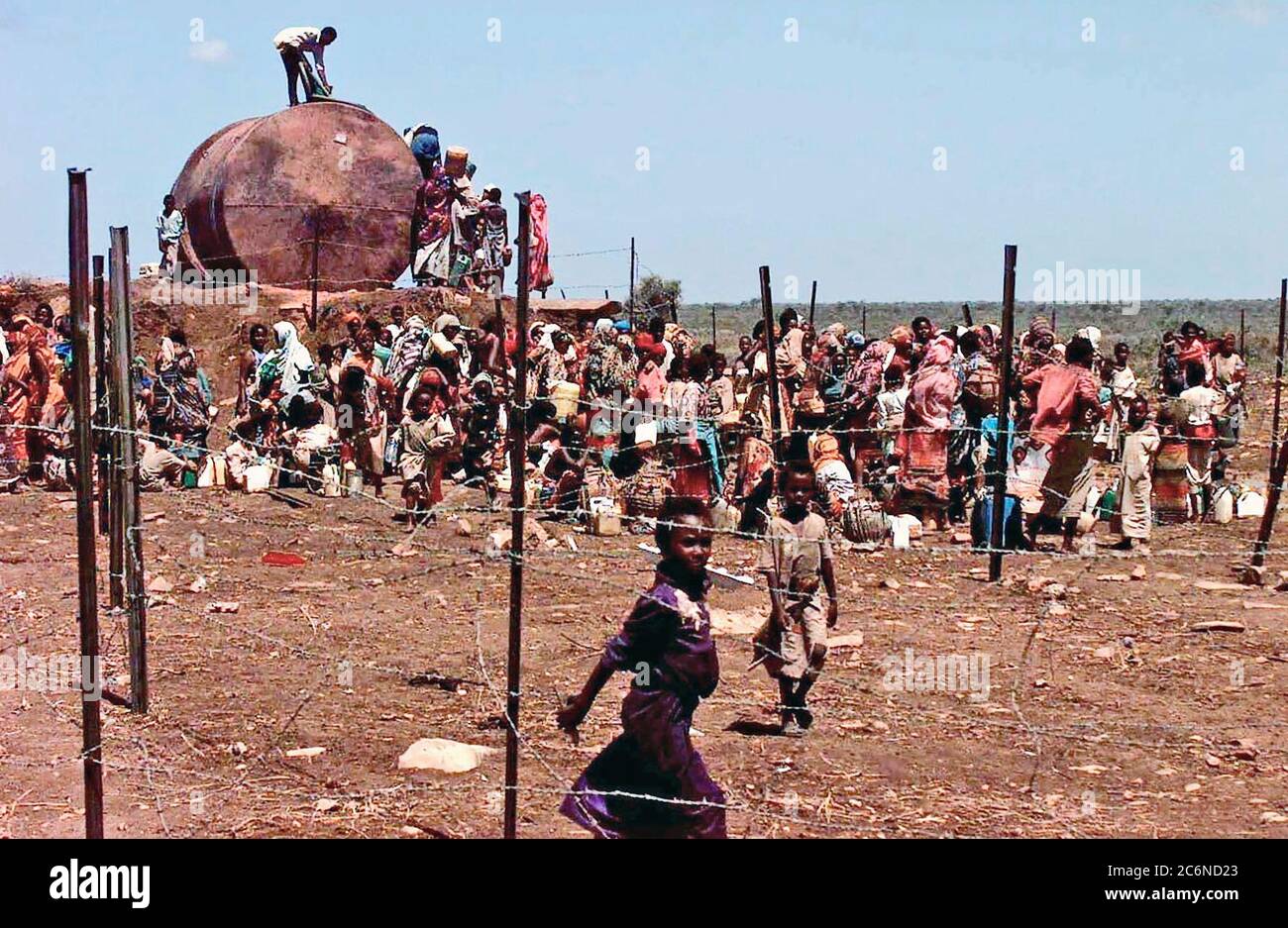 A Group of Somali refugees gathers behind barbed wire fence to get water from a well.  The well was drilled by the Indian Army to provide the refugees on Baidoa, Somalia with fresh water.  This mission is in direct support of Operation Restore Hope. Stock Photo