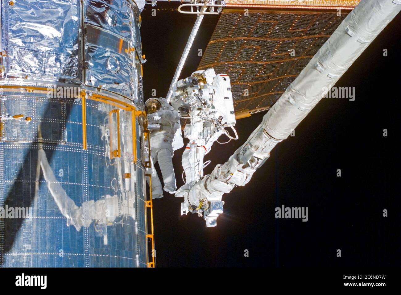 S82-E-5718 (18 Feb. 1997) --- Making use of the Remote Manipulator System (RMS) astronauts Mark C. Lee (left), STS-82 payload commander, and Steven L. Smith, mission specialist, perform the final phases of Extravehicular Activity (EVA) duty.  Lee holds a patch piece for Bay #10, out of view, toward which the two were headed.  A sample of the patch work can be seen on Bay #9 in the upper left quadrant of the picture.  This view was taken with an Electronic Still Camera (ESC). Stock Photo