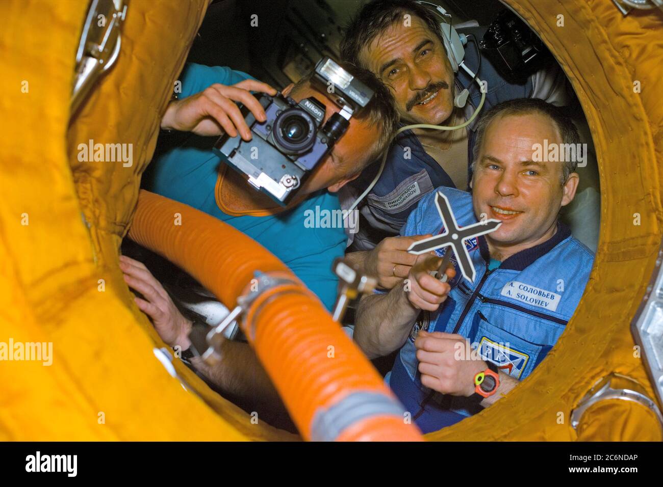 (28 Jan 1998) --- This Electronic Still Camera (ESC) image shows the Mir-24 crew having fun with the STS-89 crew just prior to the closing of the Docking Module (DM) hatch.  The closing of the hatch will bring an end to the eighth Shuttle /Mir joint docking activities.  The Mir-24 crew members are from the left - astronaut Andrew S. W. Thomas, cosmonaut guest researcher (looking through camera); cosmonaut Pavel V. Vinogradov, flight engineer (wearing communications headset); and cosmonaut Anatoliy Y. Solovyev, commander (with the stand off cross or docking target in his hand).  Thomas, replaci Stock Photo