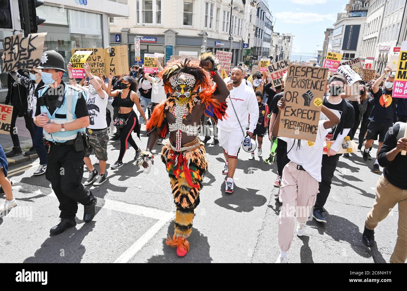 Brighton UK 11th July 2020 - Palaye Seck dressed in traditional  Senegalese costume leads thousands of protesters tin the Black Lives Matter anti racism rally in Brighton today beginning on the seafront before marching through the city centre  . There have been protests throughout America , Britain and other countries since the death of George Floyd while being arrested by police in Minneapolis on May 25th : Credit Simon Dack / Alamy Live News Stock Photo