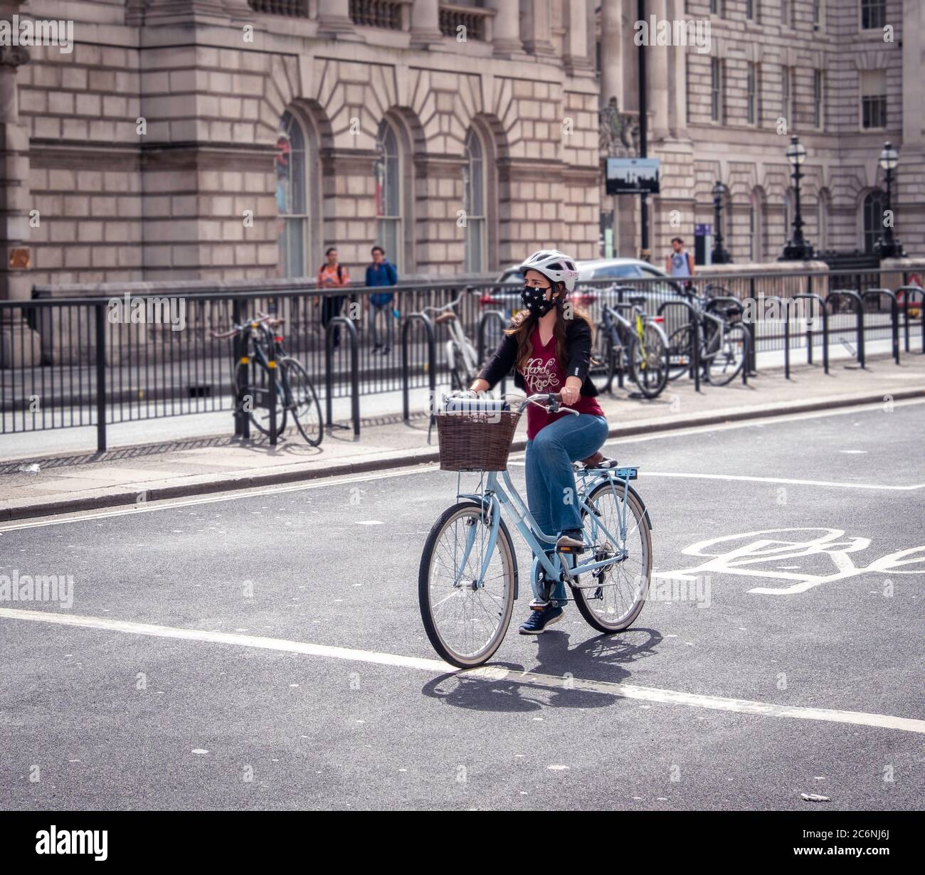 Woman with face covering on a bike at traffic lights in London during the covid-19 pandemic. Stock Photo