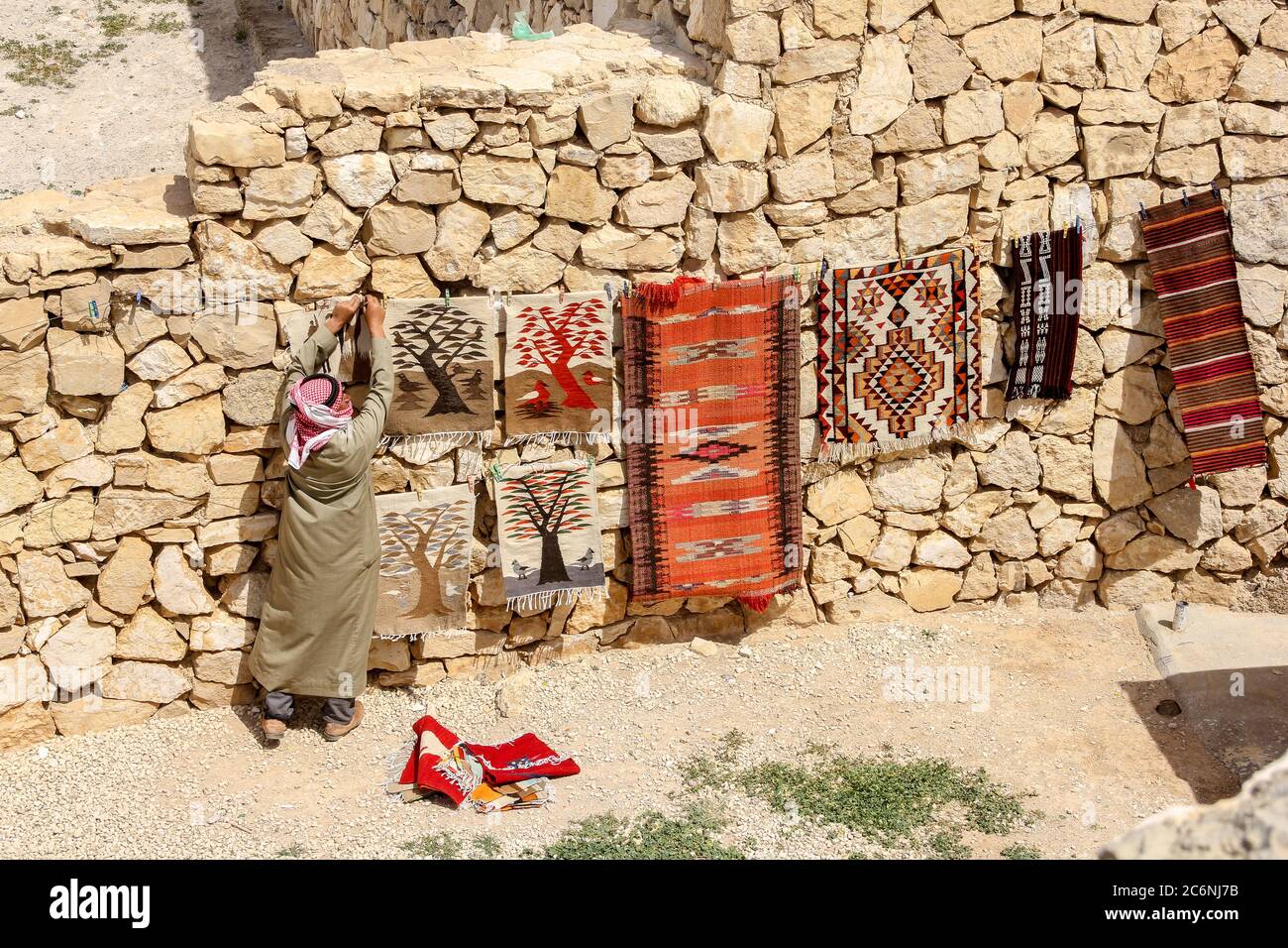 Karaka, Jordan - April 19, 2014: A man is hanging colorful carpet on the  stony roadside to sell carpet Stock Photo - Alamy