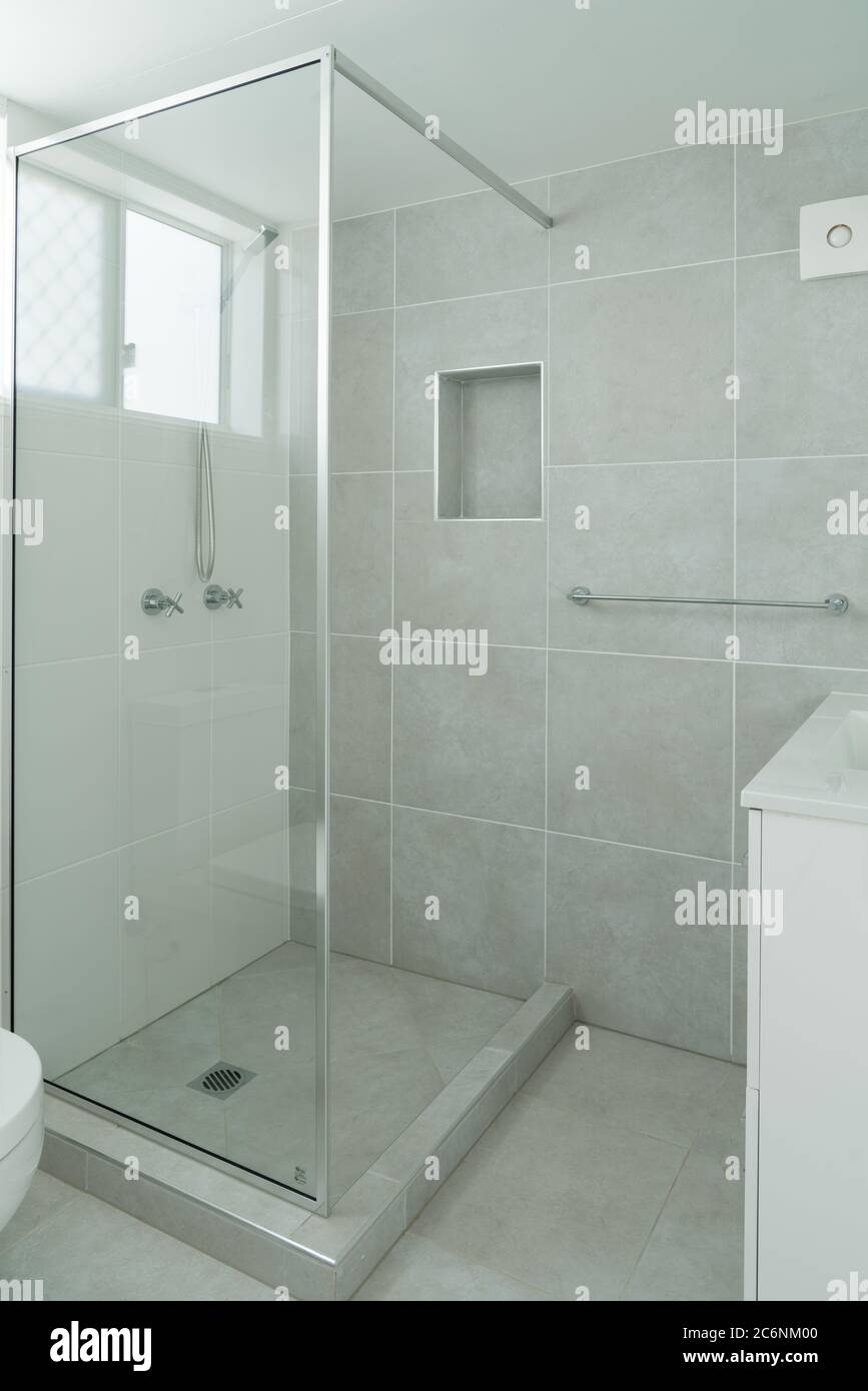 Small ensuite bathroom with show recess and tiled walls Stock Photo
