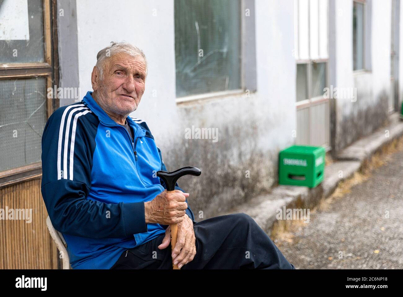 Elderly man sitting in front of the house in a village at Skadar lake, Montenegro Stock Photo