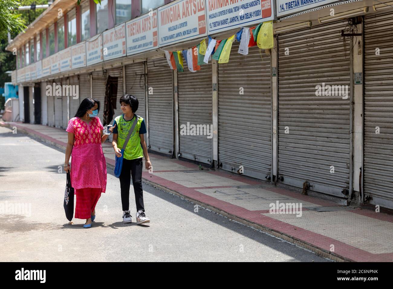 Indian woman and her son wearing corona masks infront of closed shops ...