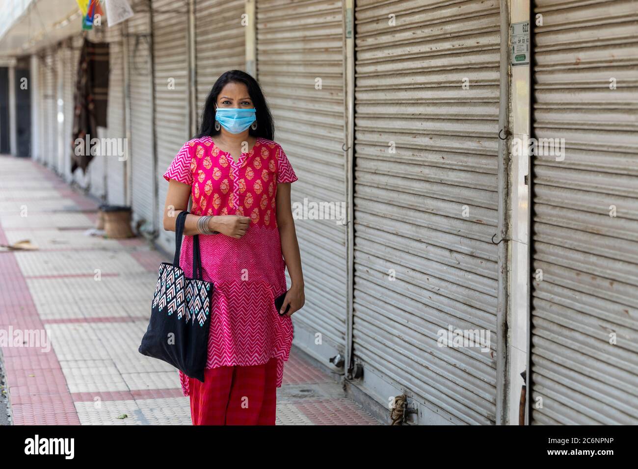 Indian lady wearing corona mask infront of closed shops on Janpath road ...