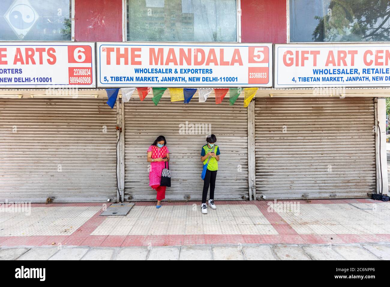 Indian woman and her son wearing corona masks infront of closed shops ...