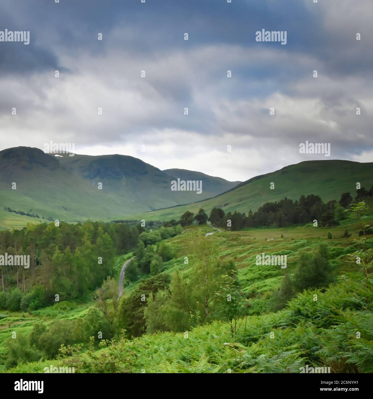 Panorama of lush green scenery in Glen Lyon, Scottish Highlands with mountains, winding road and trees. Taken from high vantage point. Stock Photo