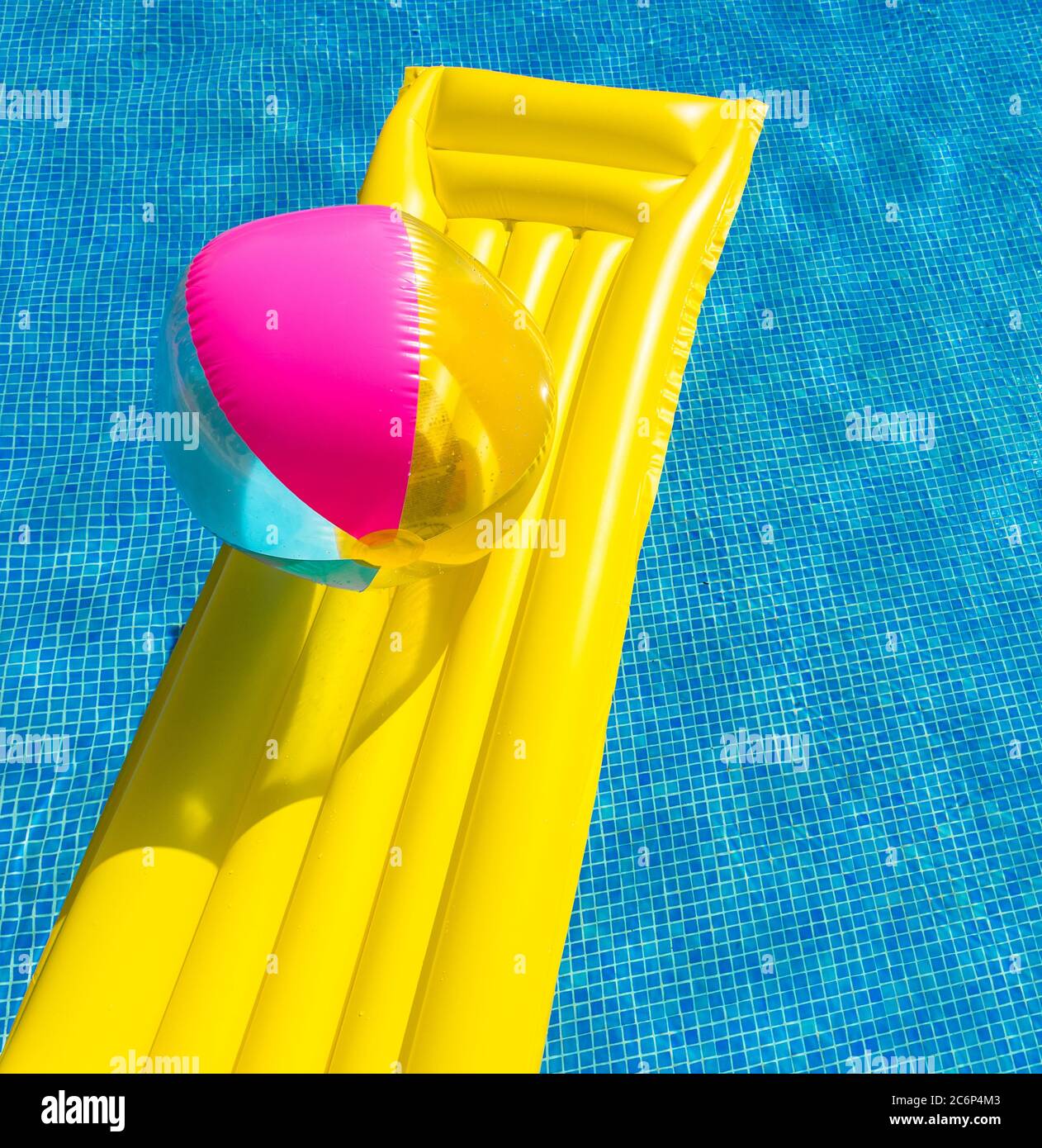 Yellow airbed and colorful beach ball float in swimming pool Stock Photo Alamy