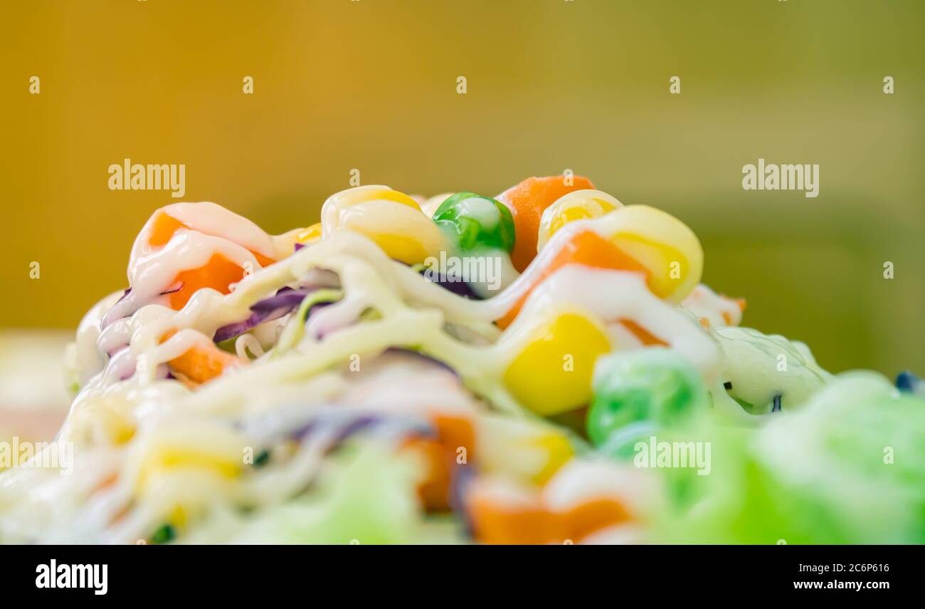 Vegetarian Salad with Mayonnaise Topping in Close Up View include Carrot and Tomato and Corn and Cabbage and Peas and Lettuce on Half Frame in Vintage Stock Photo