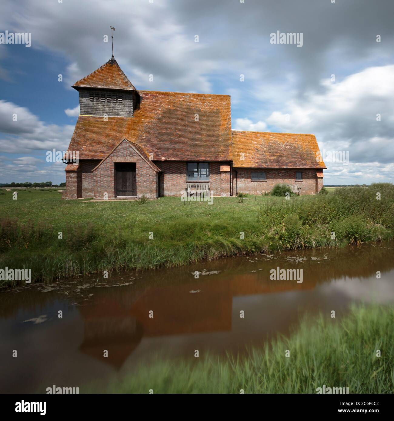 The church of St Thomas à Becket reflected in a canal near Brookland, Romney Marsh, England Stock Photo