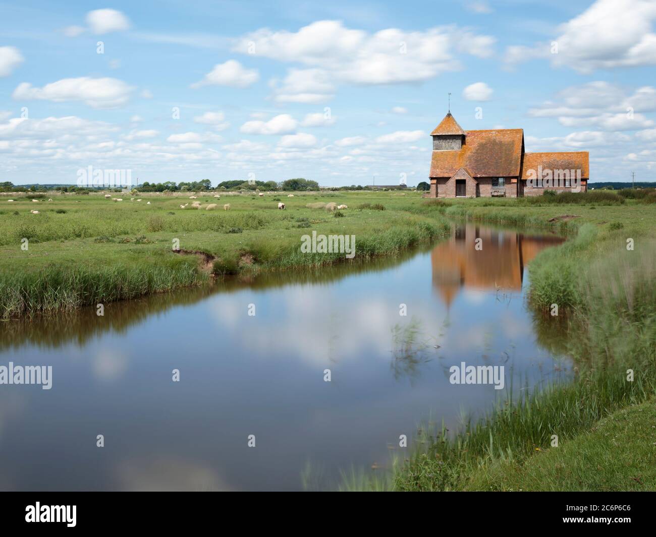 The church of St Thomas à Becket reflected in a canal near Brookland, Romney Marsh, England Stock Photo