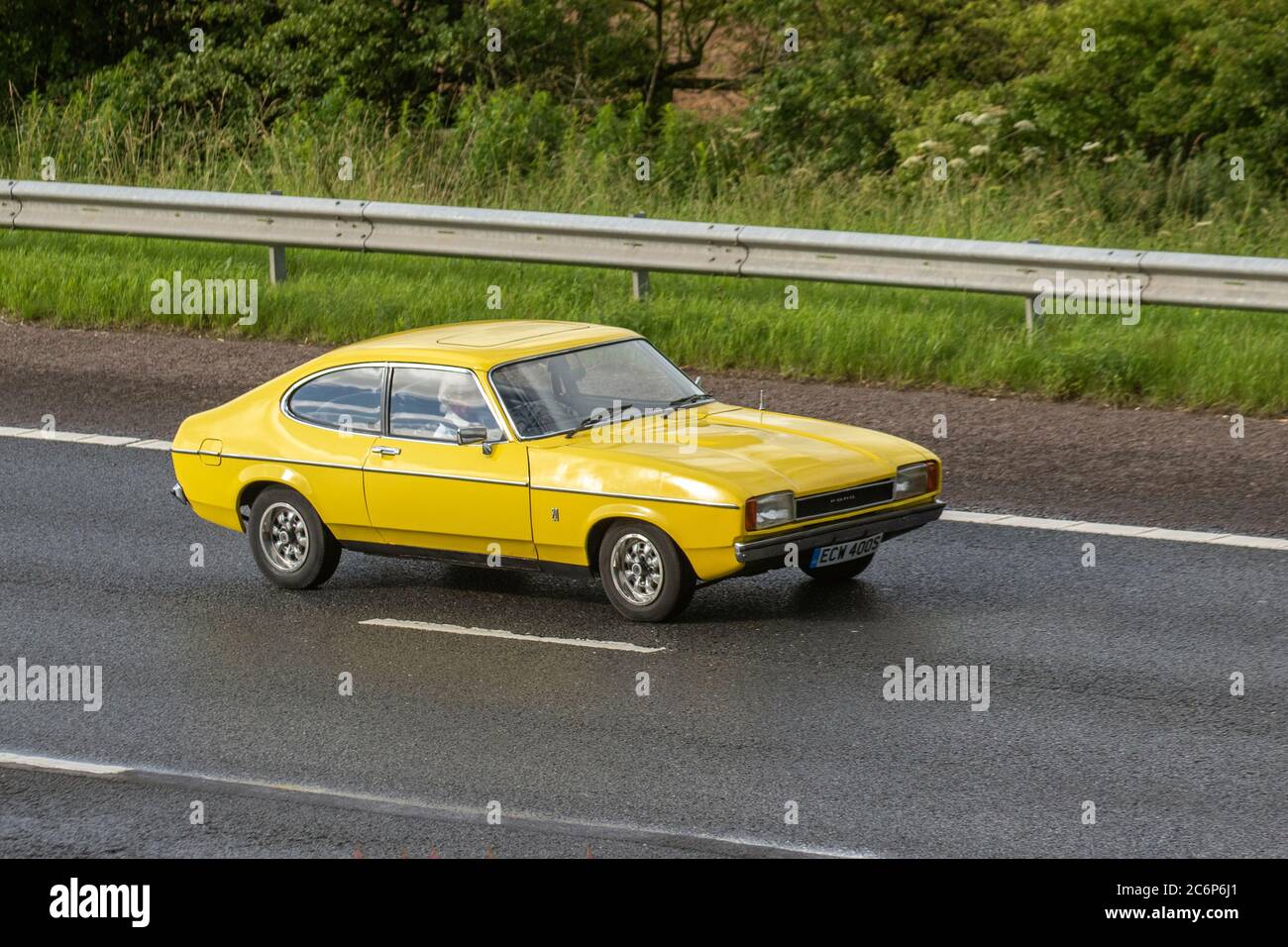 1977 70s yellow Ford Capri Ii Gl; Vehicular traffic moving vehicles, cars driving vehicle on UK roads, classic cars, cherished, veteran,  restored old timer, collectible motors, vintage, heritage, old preserved, collectable motors, motoring on the M6 motorway highway network. Stock Photo