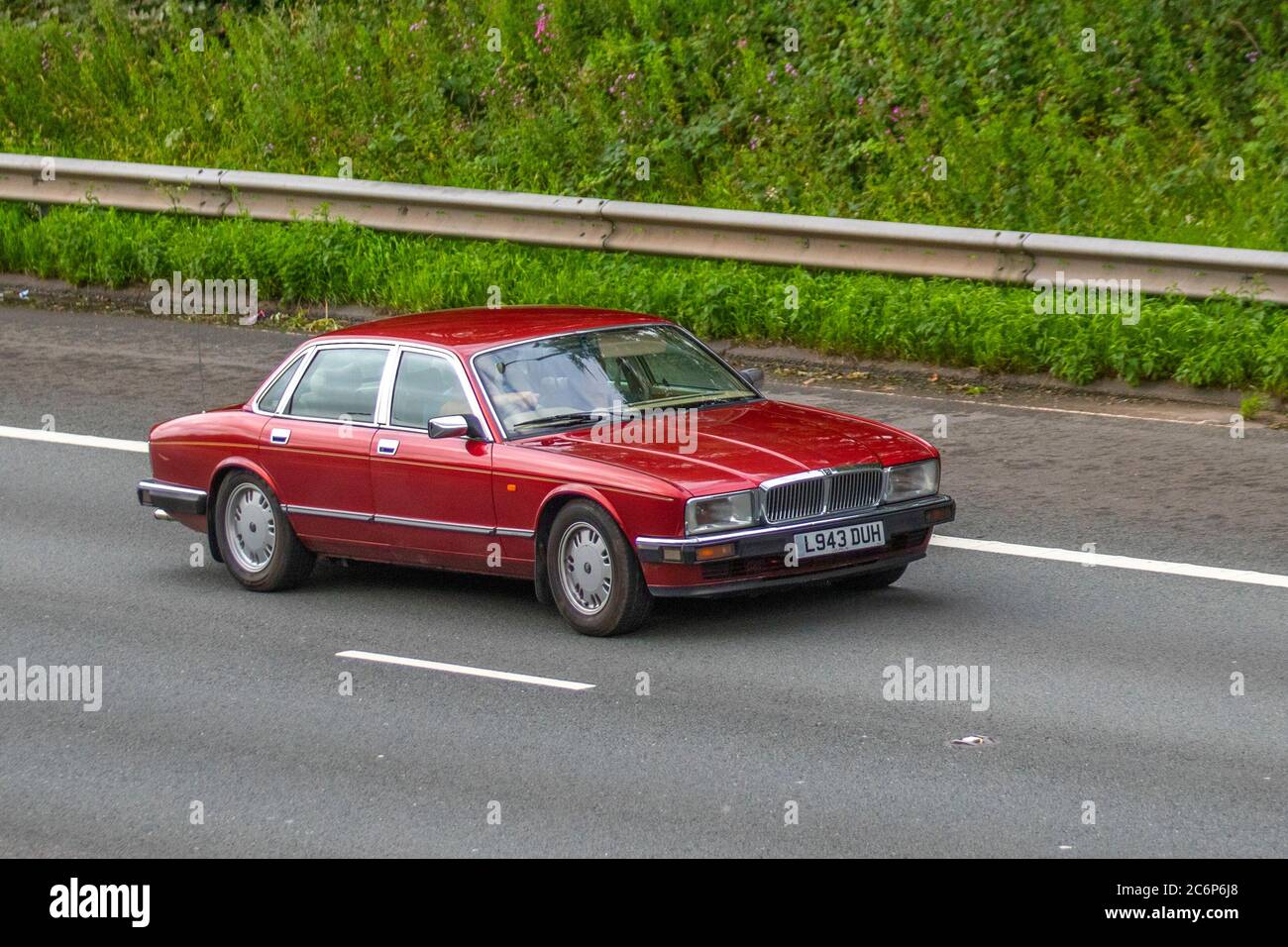 1994 90s nineties Red Jaguar Sovereign 4.0 Auto; Vehicular traffic moving vehicles, cars driving on UK roads, classic cars, cherished, veteran,  restored old timer vehicle, collectable motors, vintage, heritage, old preserved, collectable motors, motoring on the M6 motorway highway network. Stock Photo