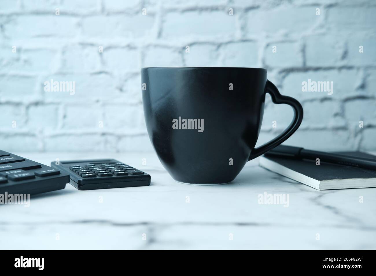 Black mug mockup with with keyboard, notebooks on table  Stock Photo