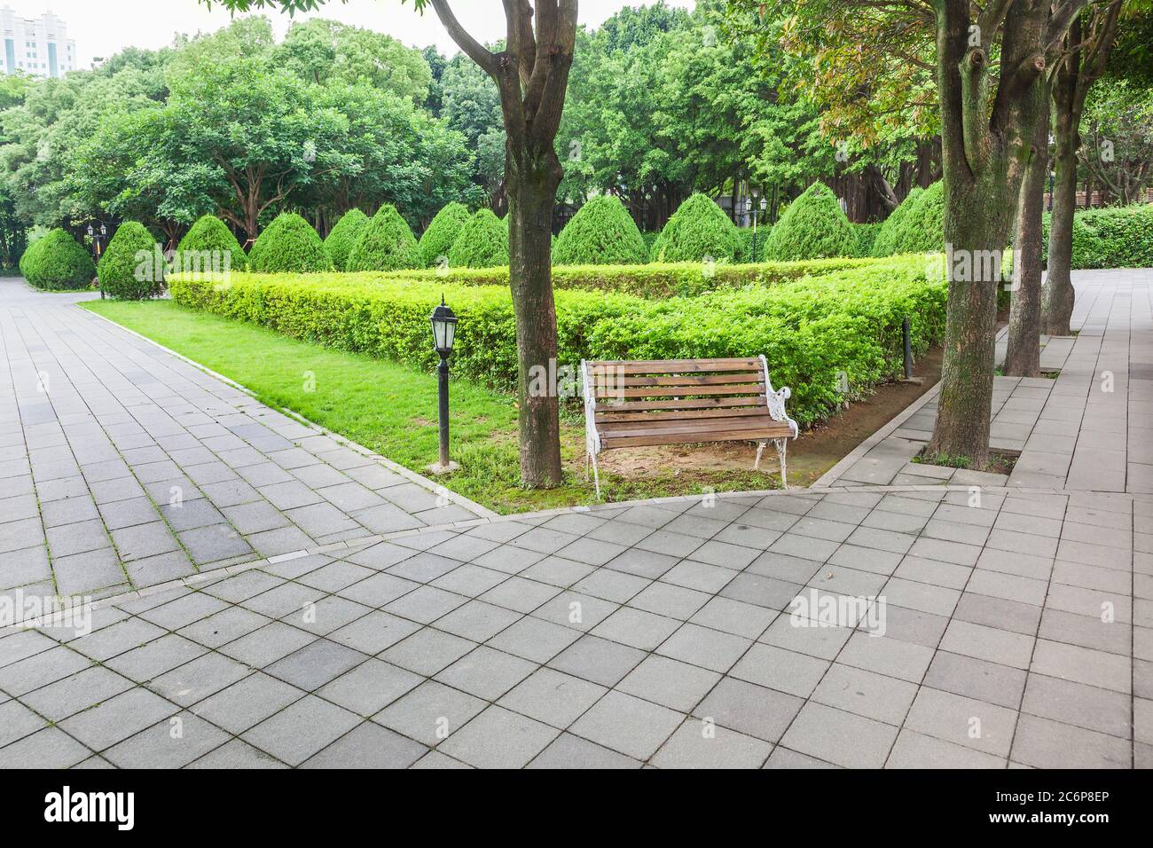 View of green garden with a small square and wooden bench for resing in the corner of the city park,Fuzhou,Fujian,China Stock Photo
