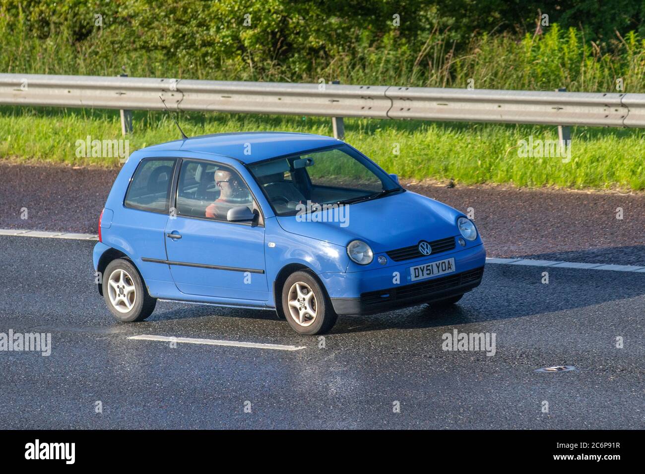 2015 blue VW Volkswagen Polo SE TDI; Vehicular traffic moving vehicles, cars driving vehicle on wet UK roads, motors, motoring on the M6 motorway highway network. Stock Photo