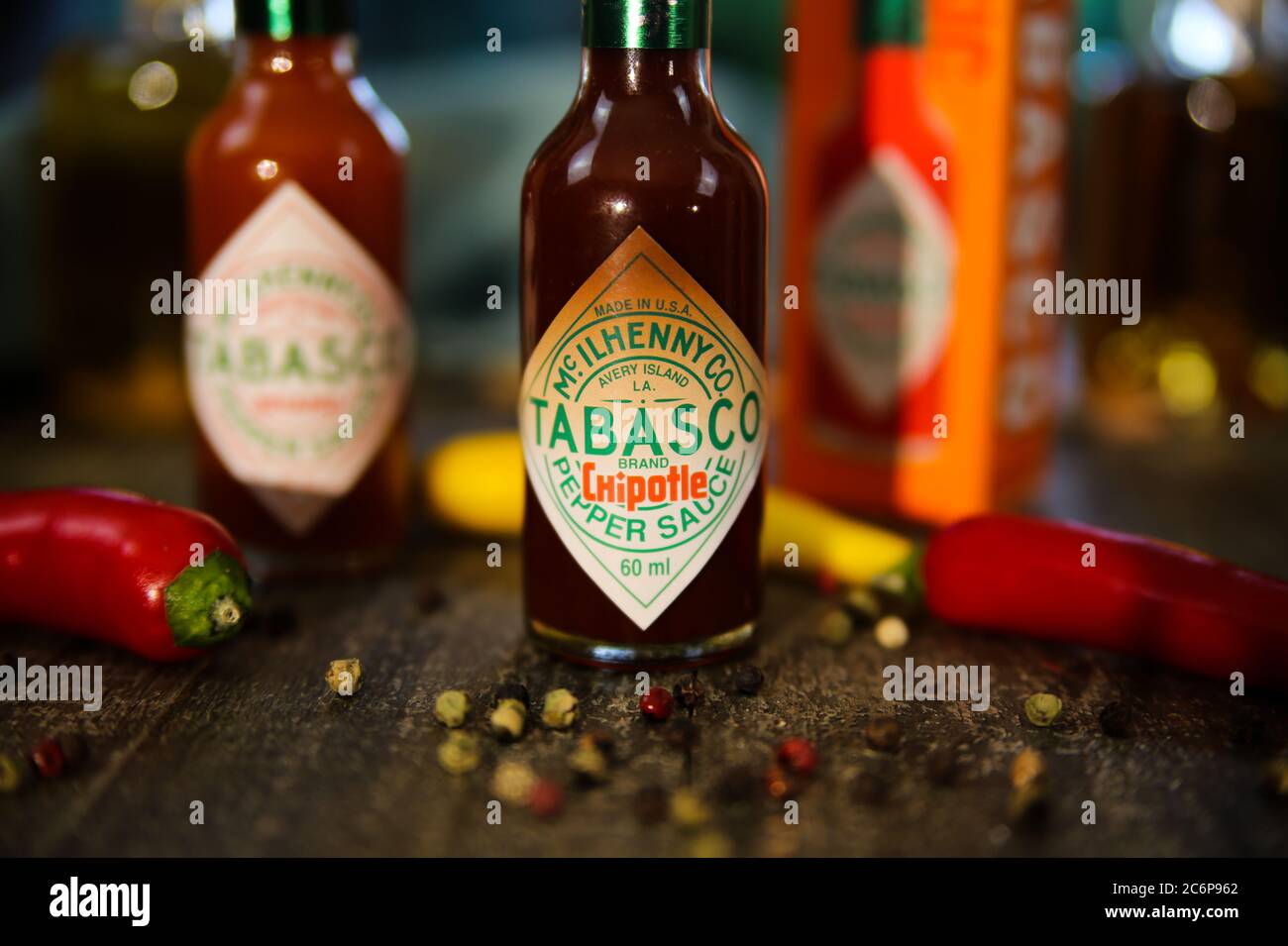 Viersen, Germany - July 9. 2020: Closeup of Tabasco hot chipotle pepper sauce on wood table with peppercorns and chillis Stock Photo